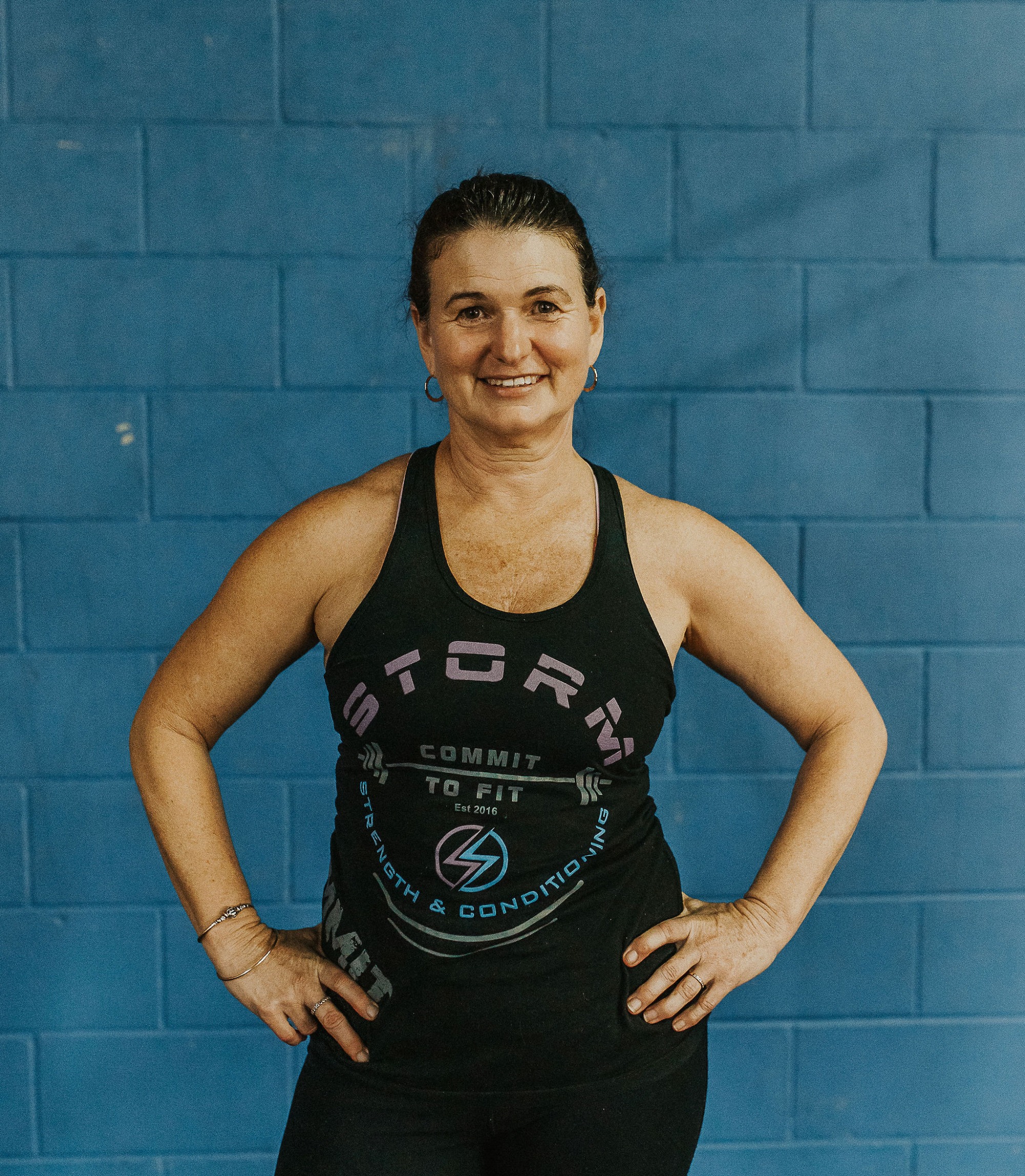 Coach Tracey standing in a Storm singlet in front of the blue gym wall
