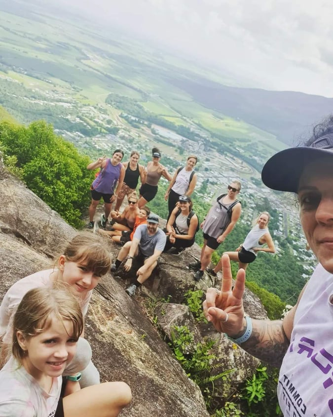 Group posing at the summit of a mountain climb above the valley