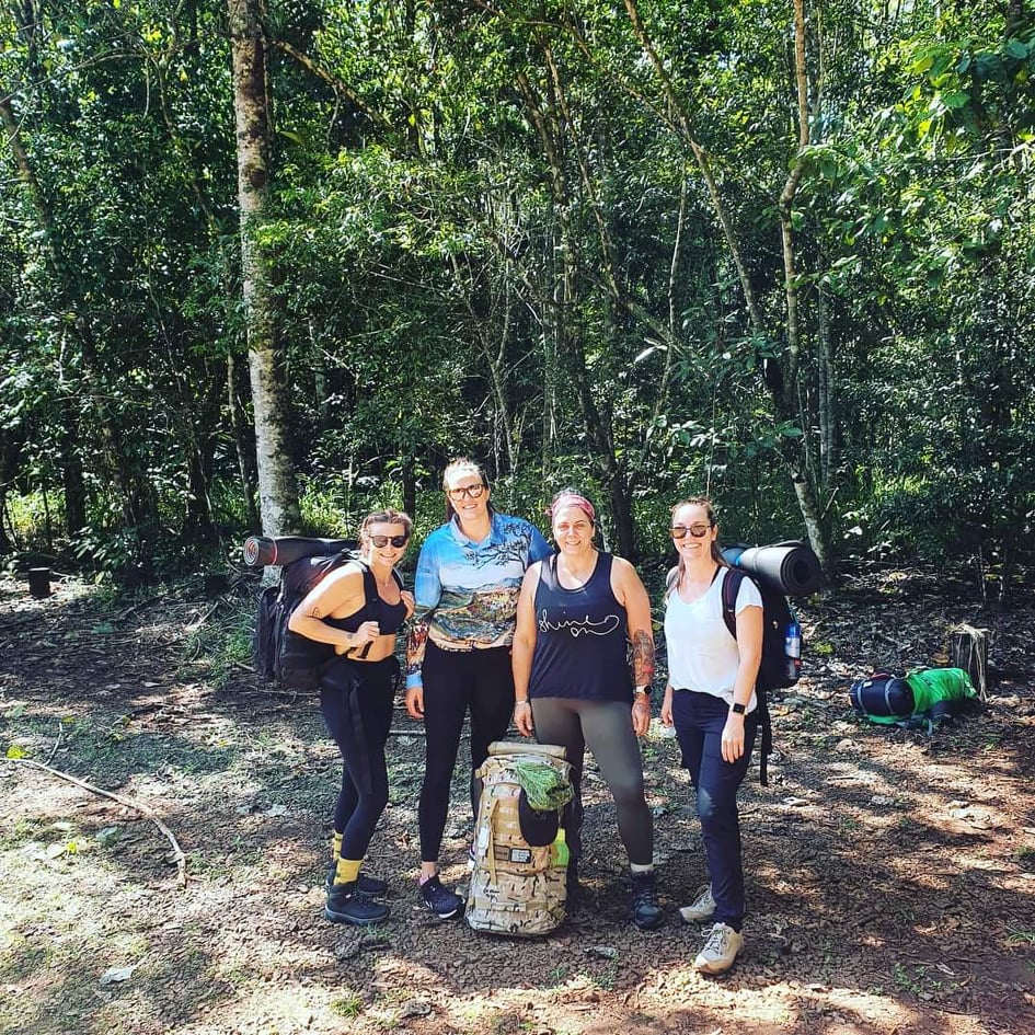 Members gathered around a log on a rainforest trek