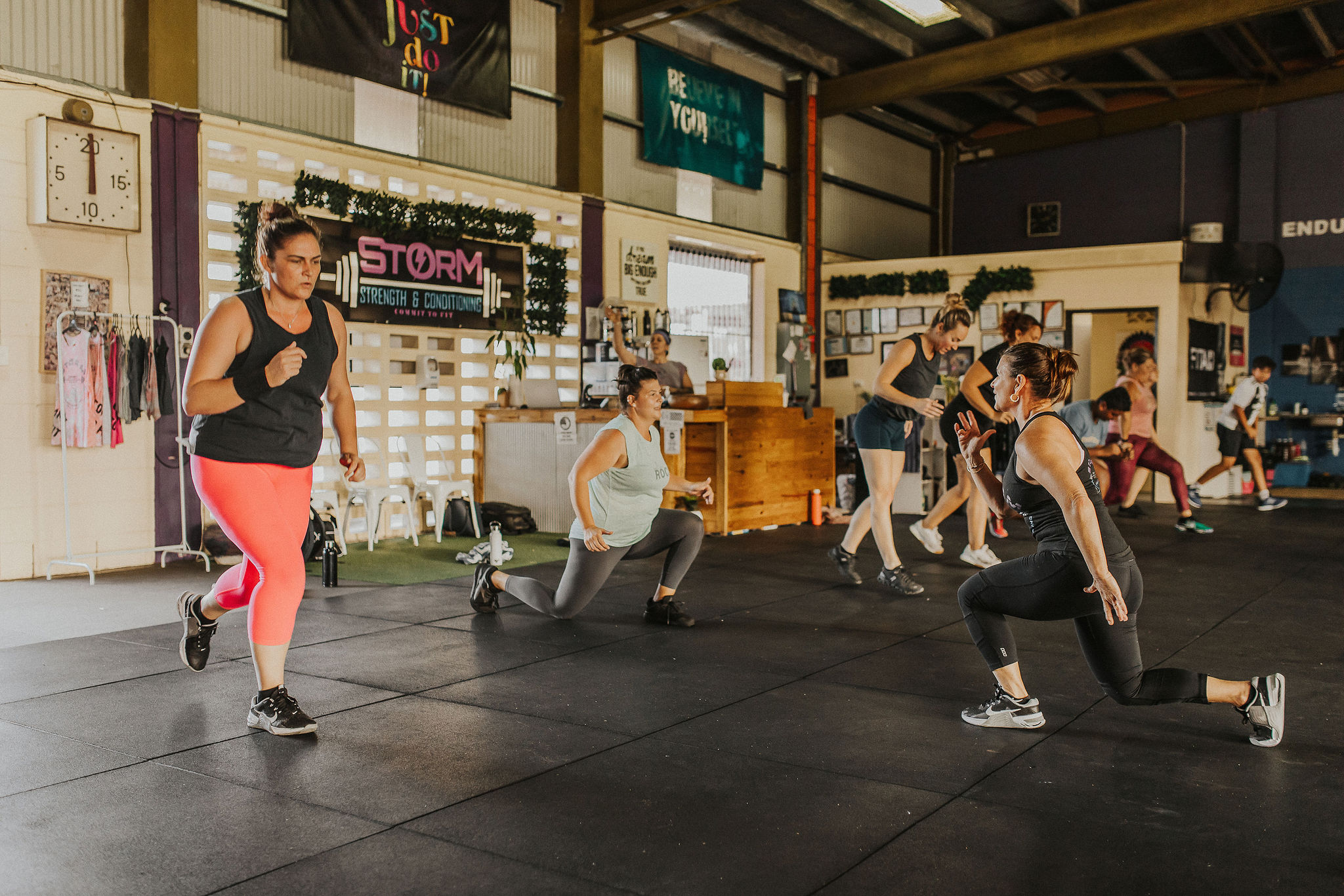 Row of members holding a plank position along the gym wall during a HIIT class