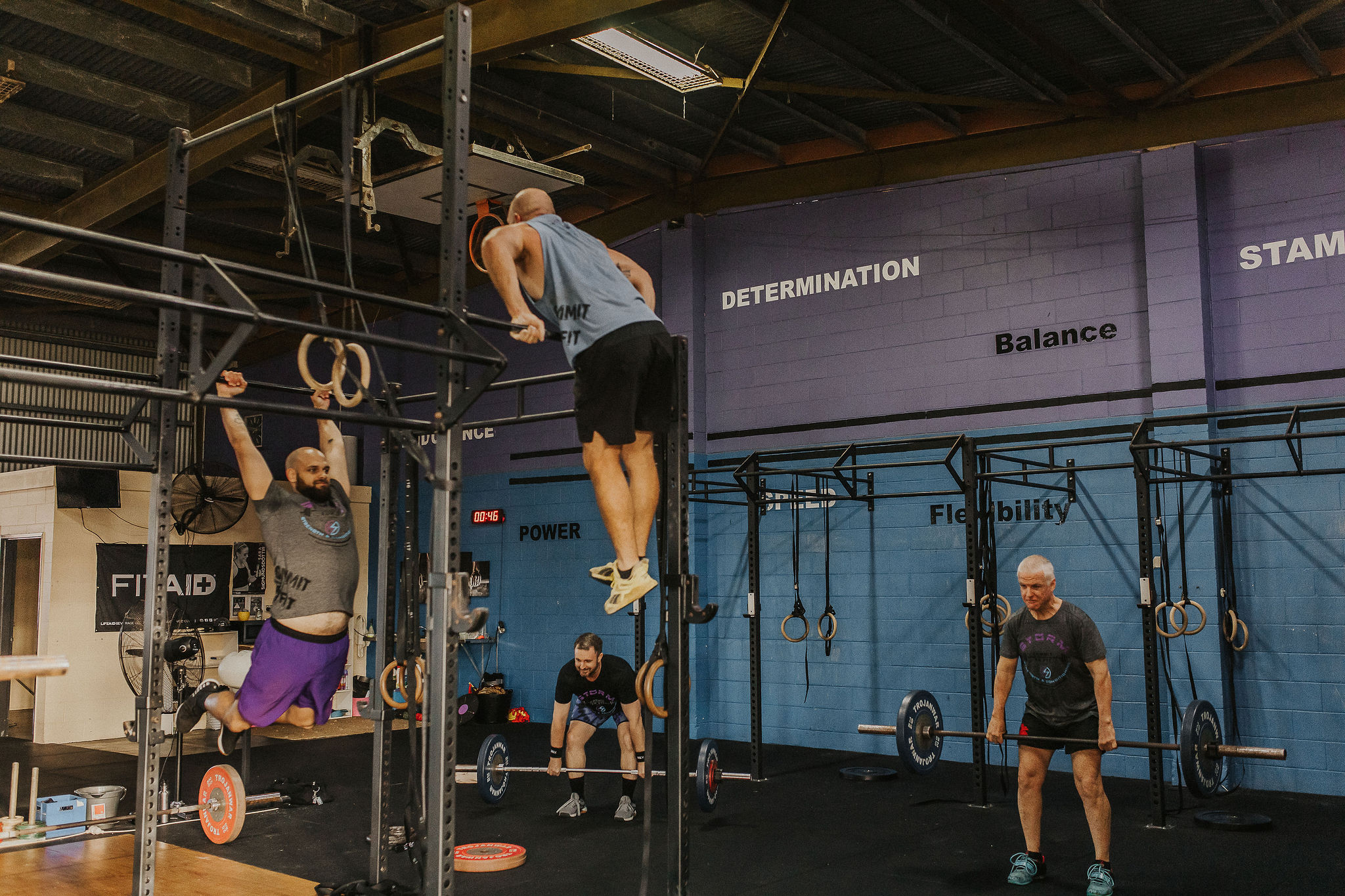 Members lifting barbells together on the gym floor during a strength session
